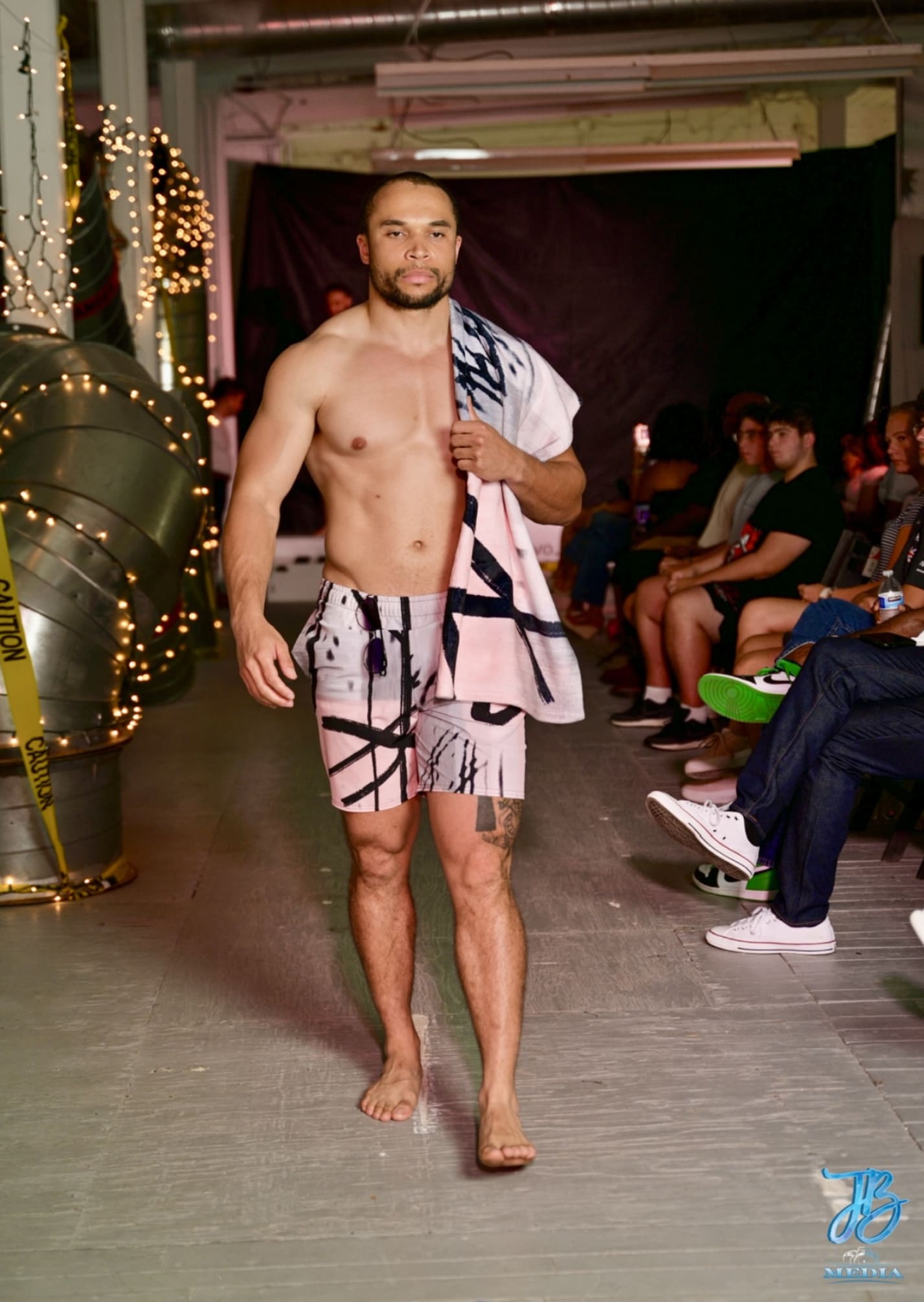 A man in swim trunks and towel on the runway.