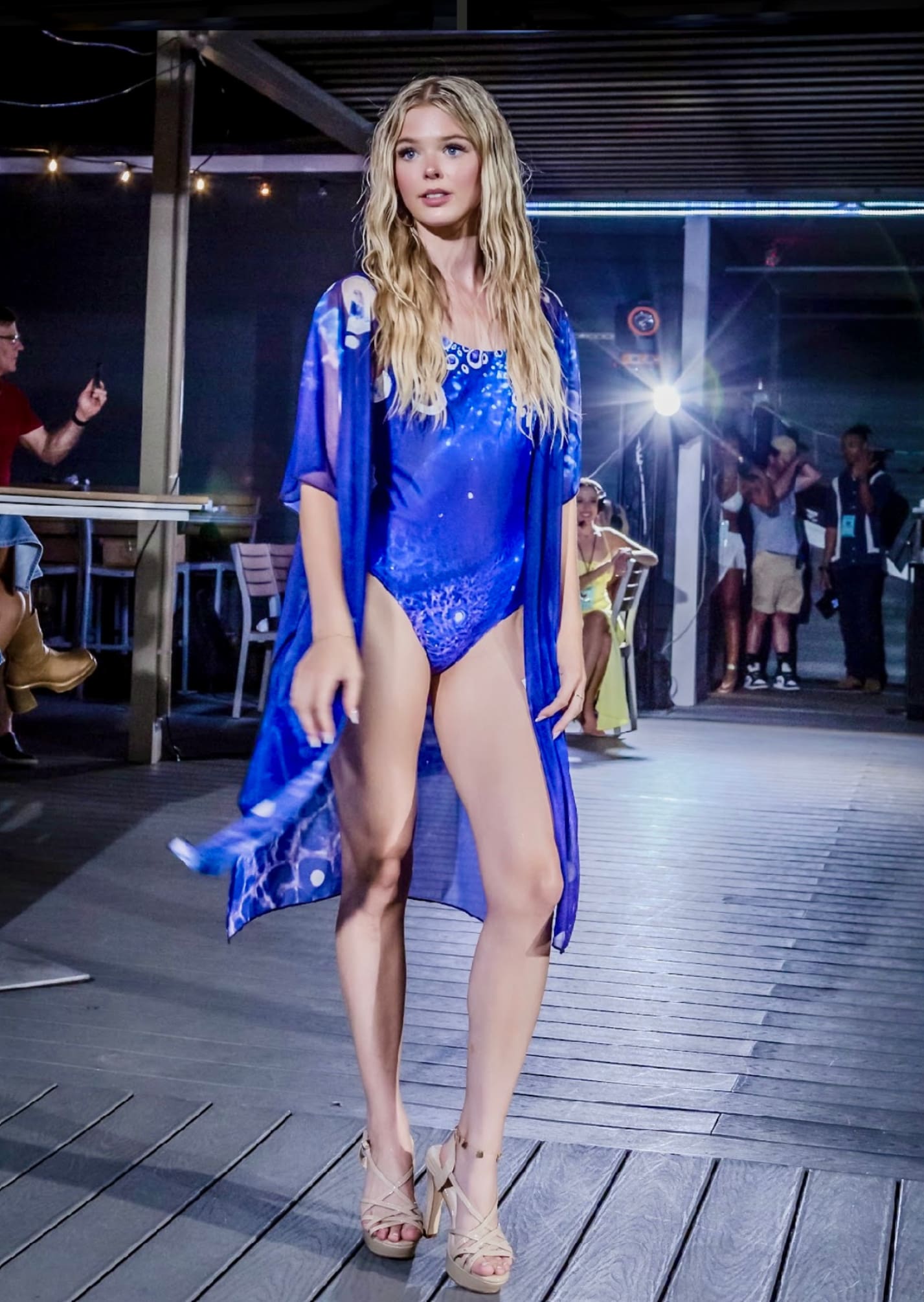 A woman in blue bathing suit and robe on runway.