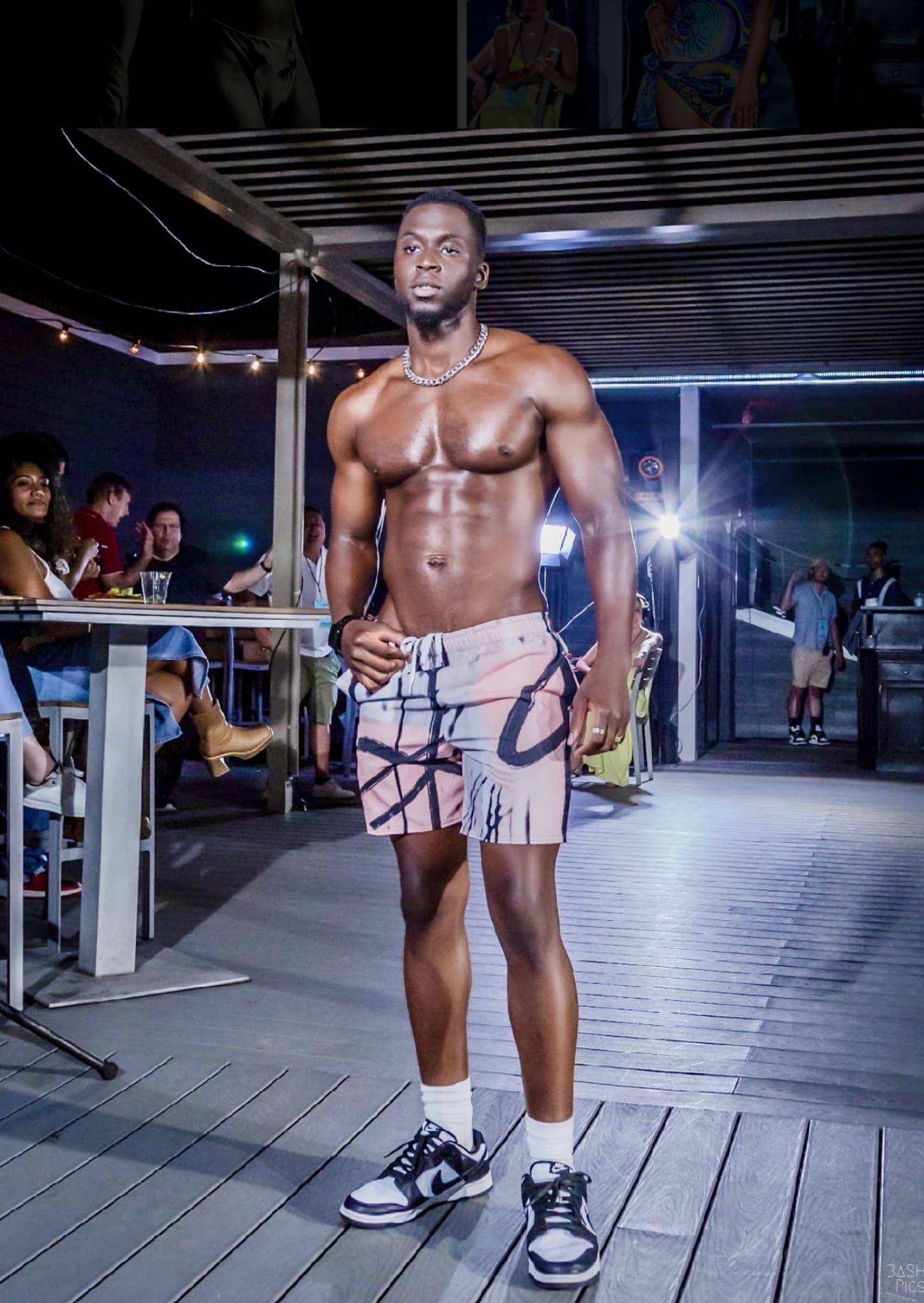 A man in shorts and no shirt standing on the runway.