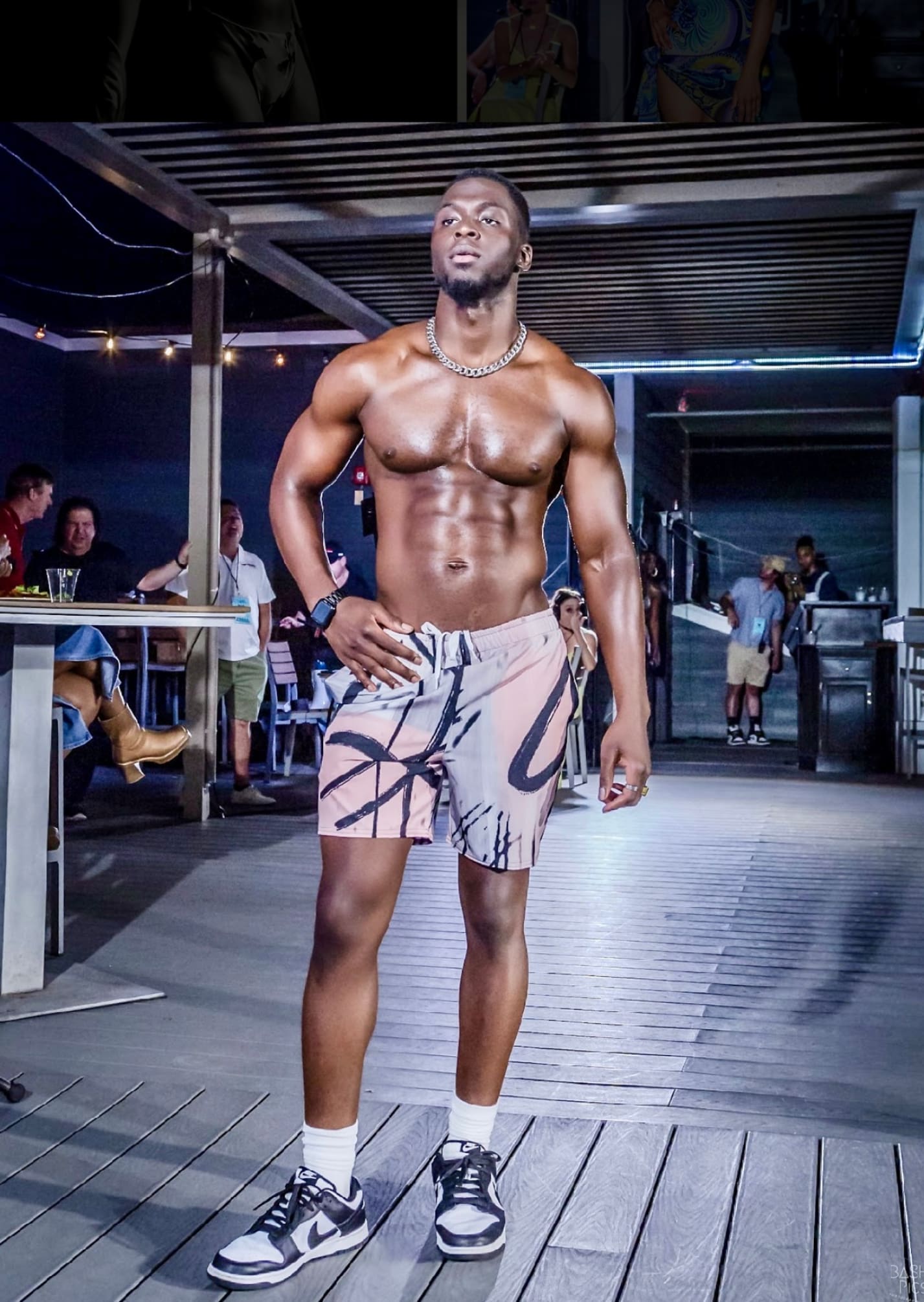 A man in swim trunks standing on the runway.