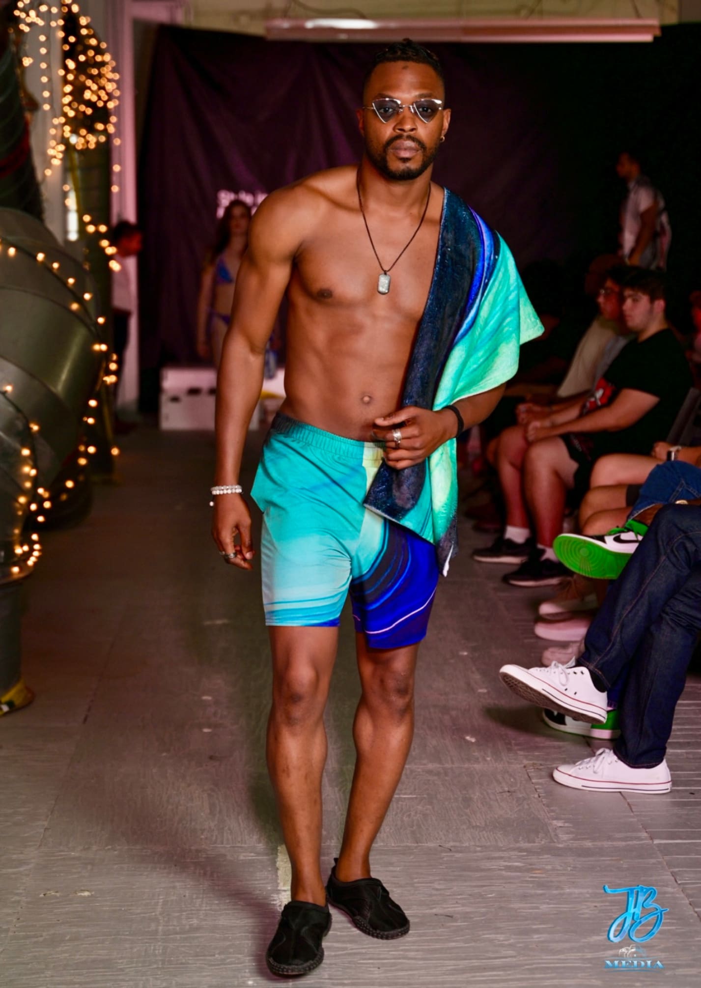 A man in blue shorts and a towel on his shoulder.