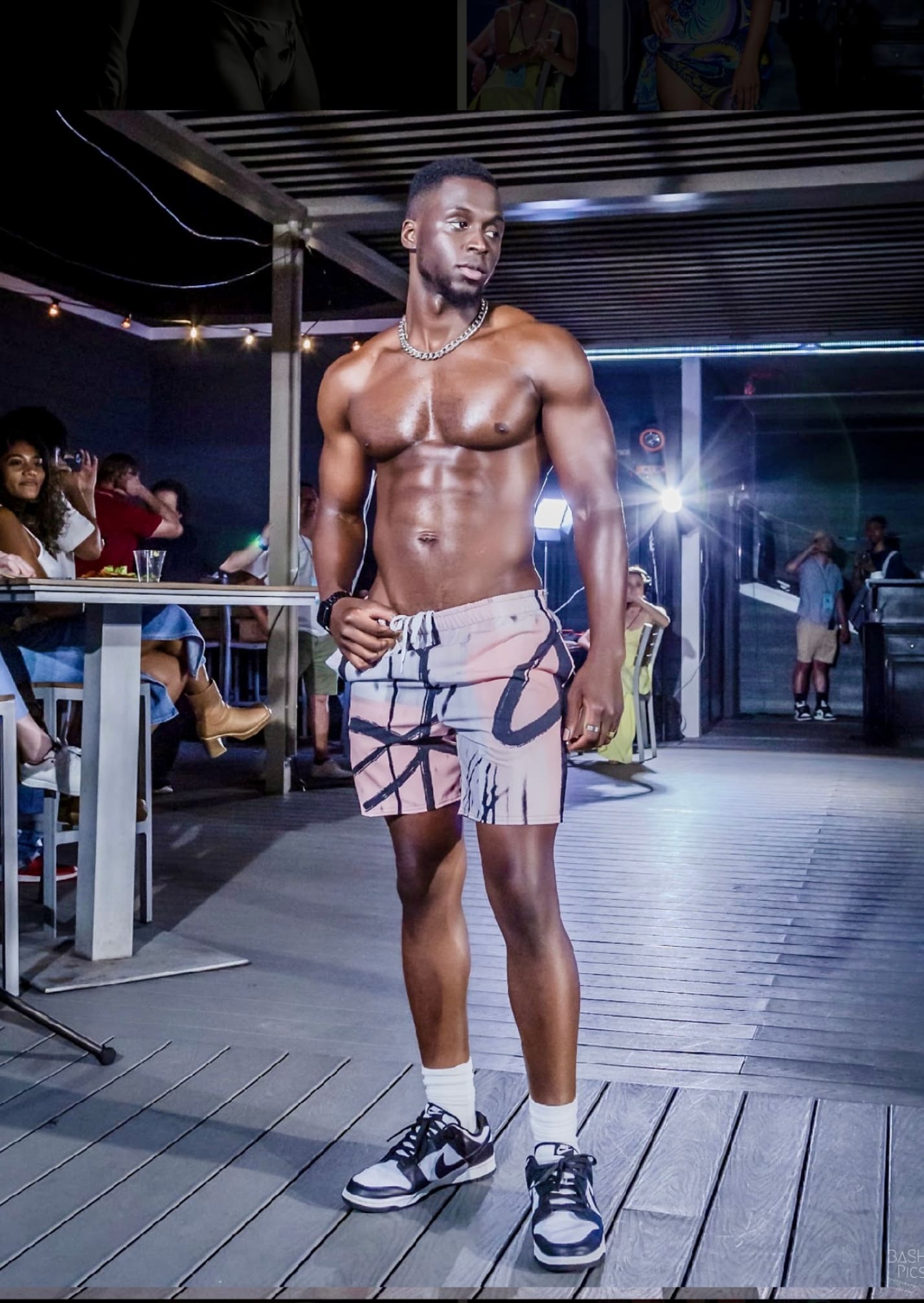 A man in swim trunks standing on the runway.