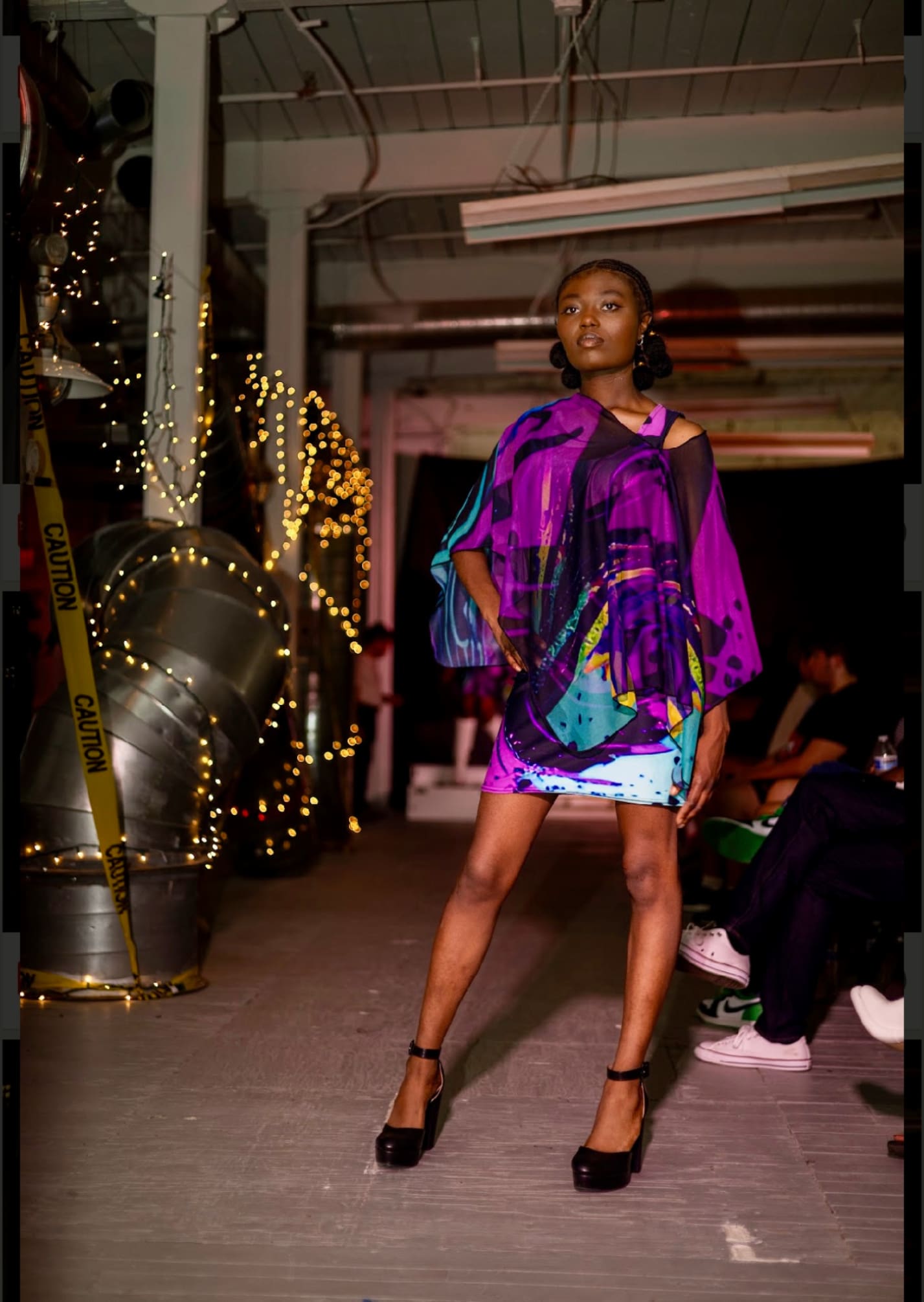 A woman in purple and blue dress standing on the runway.