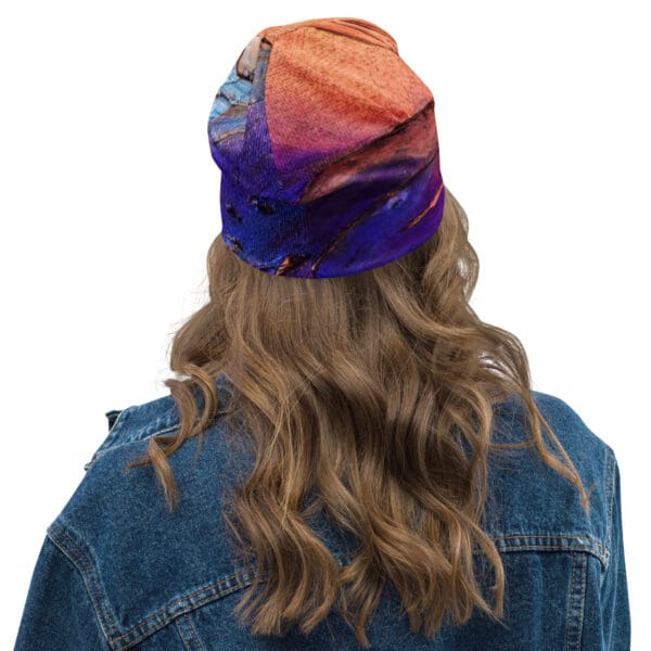 A woman with long hair wearing a denim jacket and a colorful hat.