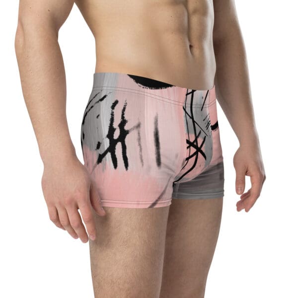 A man wearing pink and gray trunks with black writing.