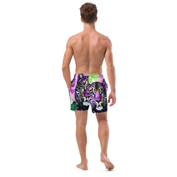 A man wearing swim trunks with an image of trees.