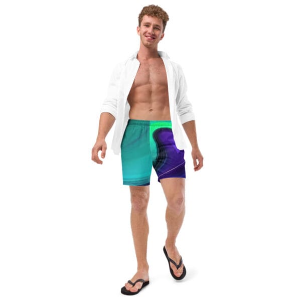 A man in blue and green swim trunks standing next to a white shirt.