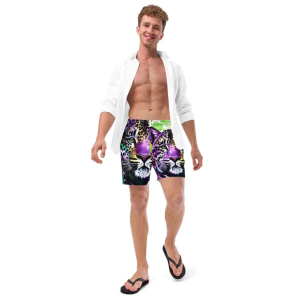 A man in swim trunks and flip flops standing up.