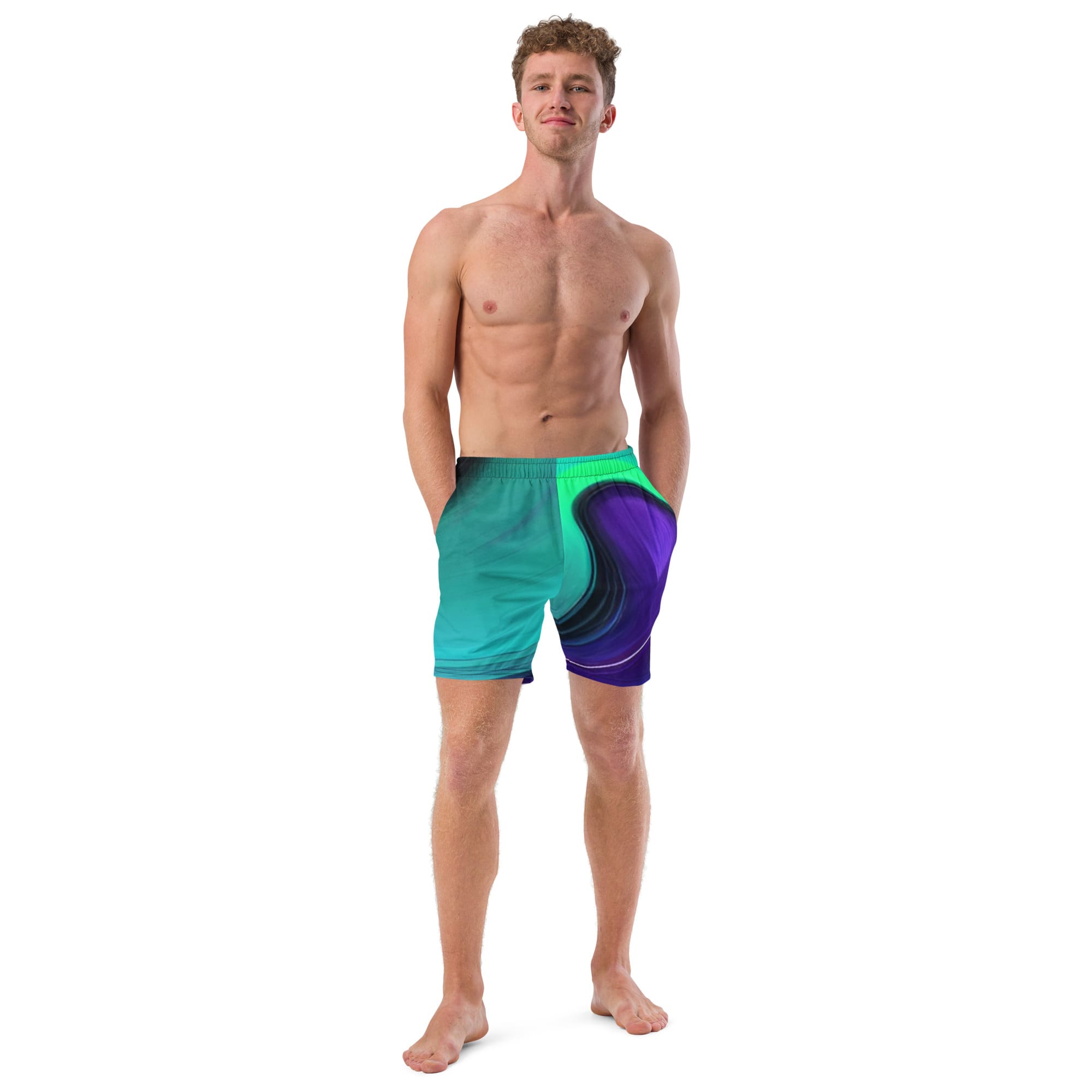 A man standing in front of the camera wearing blue and purple swim trunks.