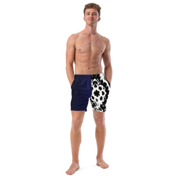 A man standing in front of the camera wearing blue swim trunks.