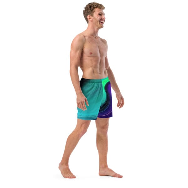 A man in swim trunks walking on the beach.