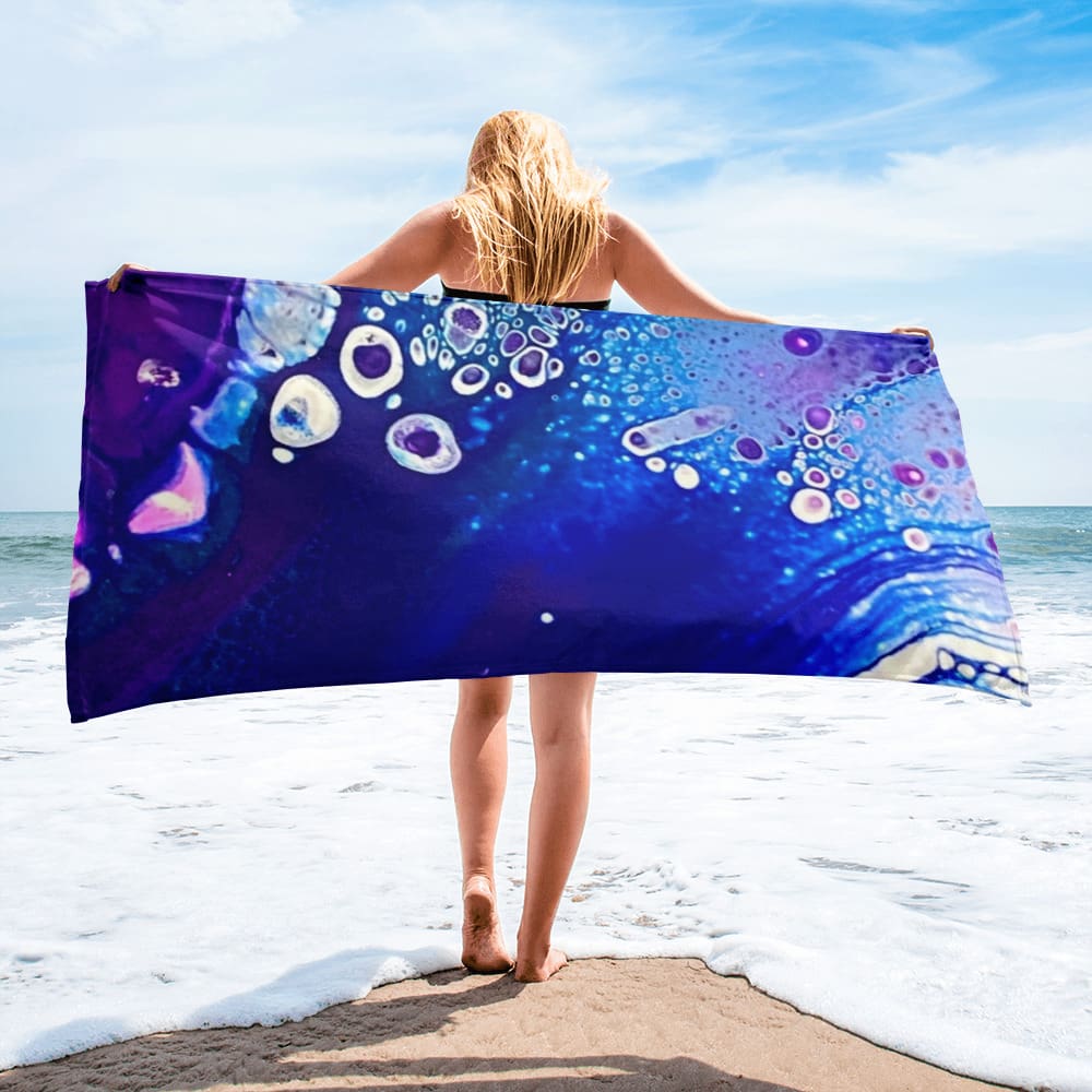 A woman standing on the beach holding onto a towel