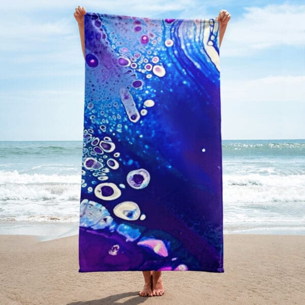 A person standing on the beach holding up a towel