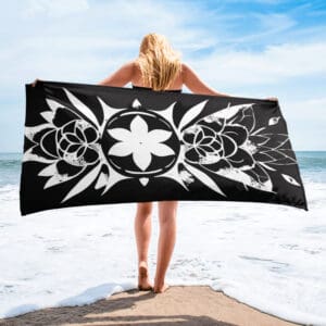 A woman standing on the beach holding onto a towel