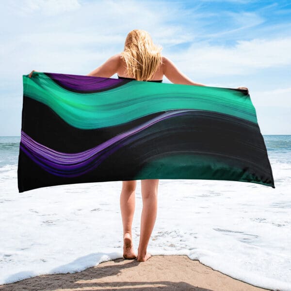 A woman standing on the beach holding onto a towel