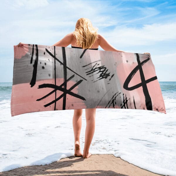 A woman standing on the beach holding onto a towel