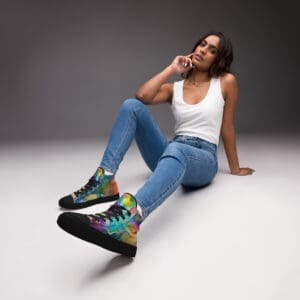 A woman sitting on the ground wearing blue jeans and black shoes.