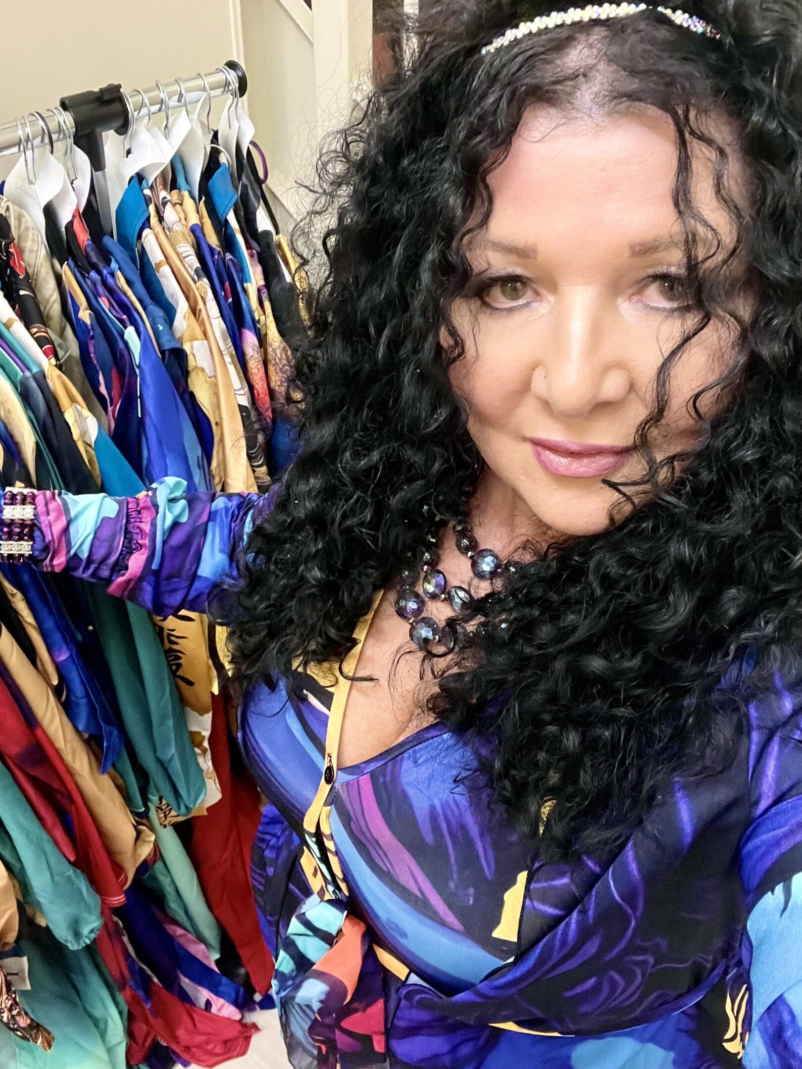 Woman in colorful dress near clothing rack.