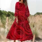 Woman wearing red rose-patterned dress outdoors.