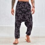 Man wearing patterned harem pants, tattoos visible.