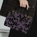 Person holding patterned handbag, plaid coat.