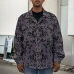 Man wearing a patterned gray jacket outside.