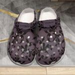 Purple floral-patterned clogs on geometric rug.